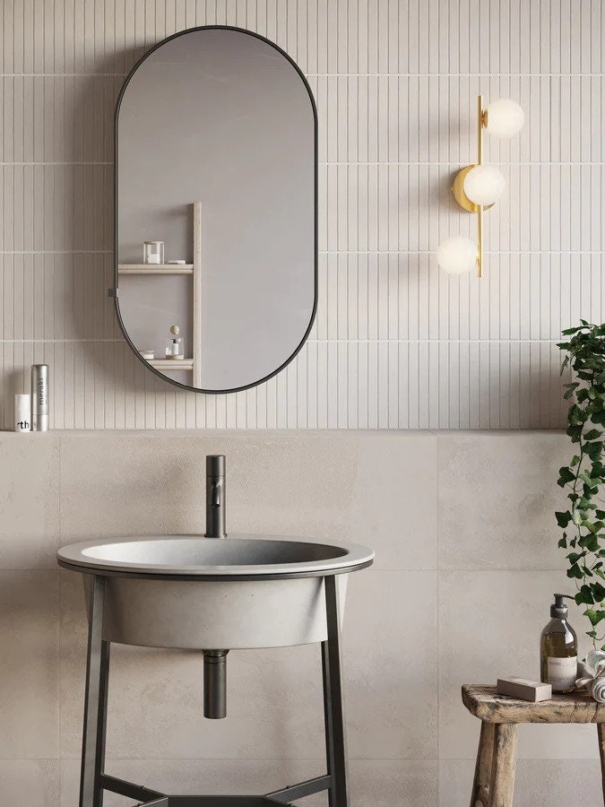 Bathroom with oval mirror, sink, and wall lights
