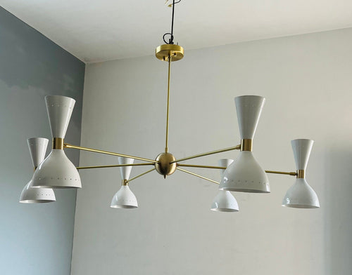 Modern chandelier with white lampshades and gold accents against a light gray wall.
