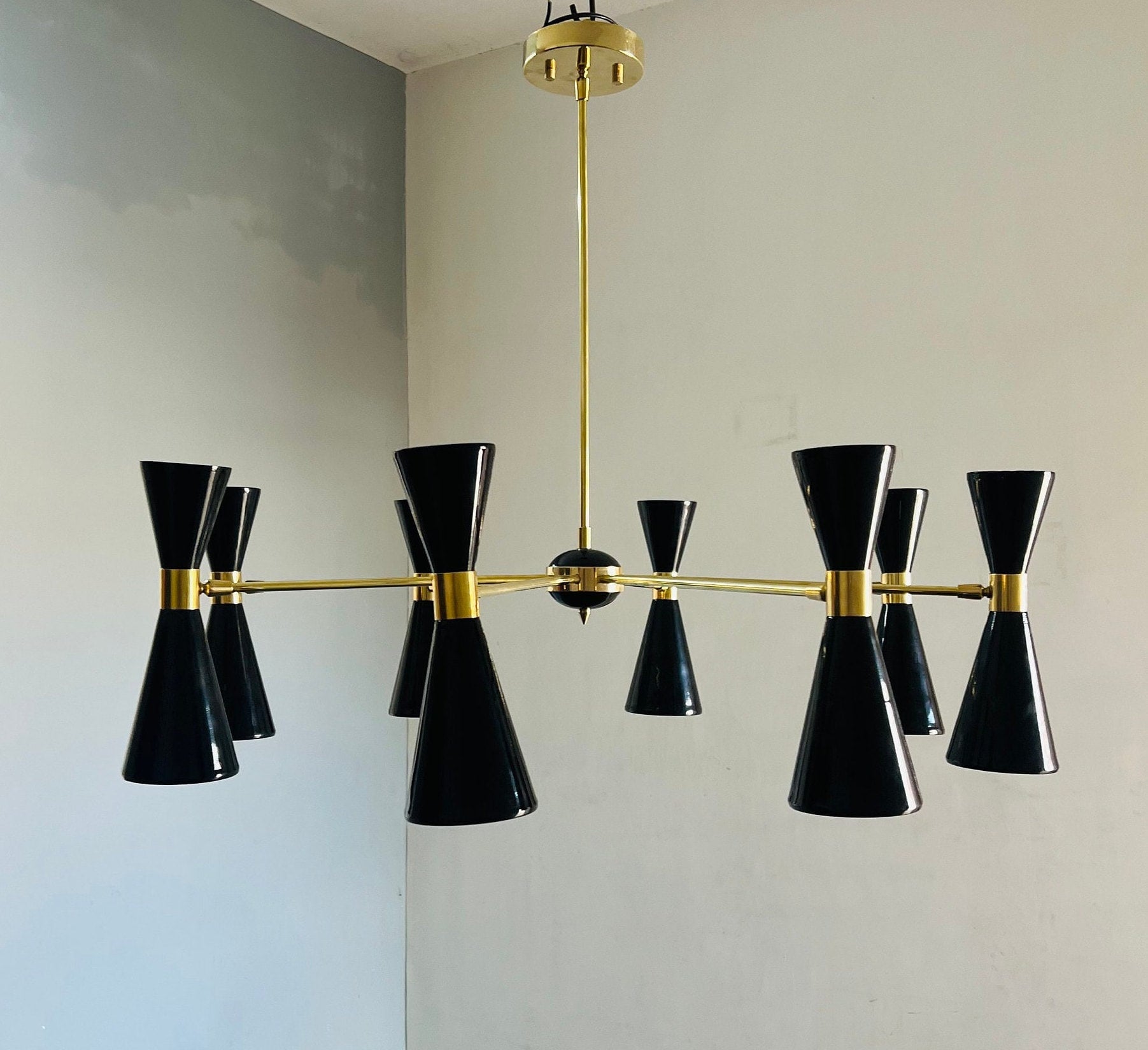 Modern chandelier with black and gold design on a neutral wall.