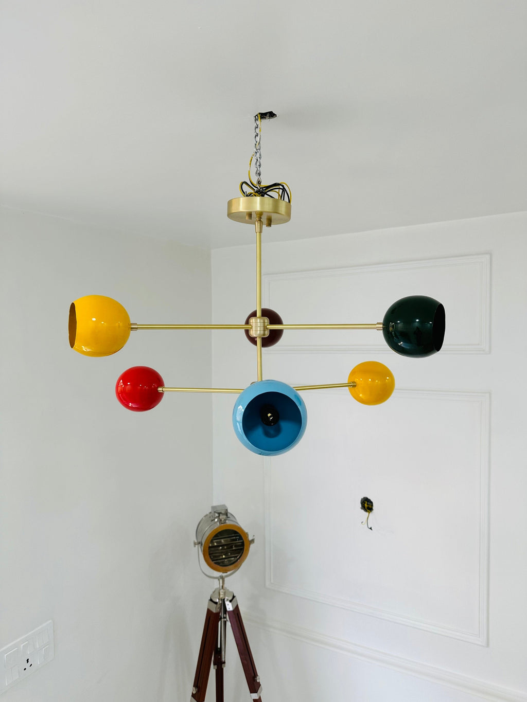Colorful chandelier with multicolored lampshades hanging from a white ceiling.