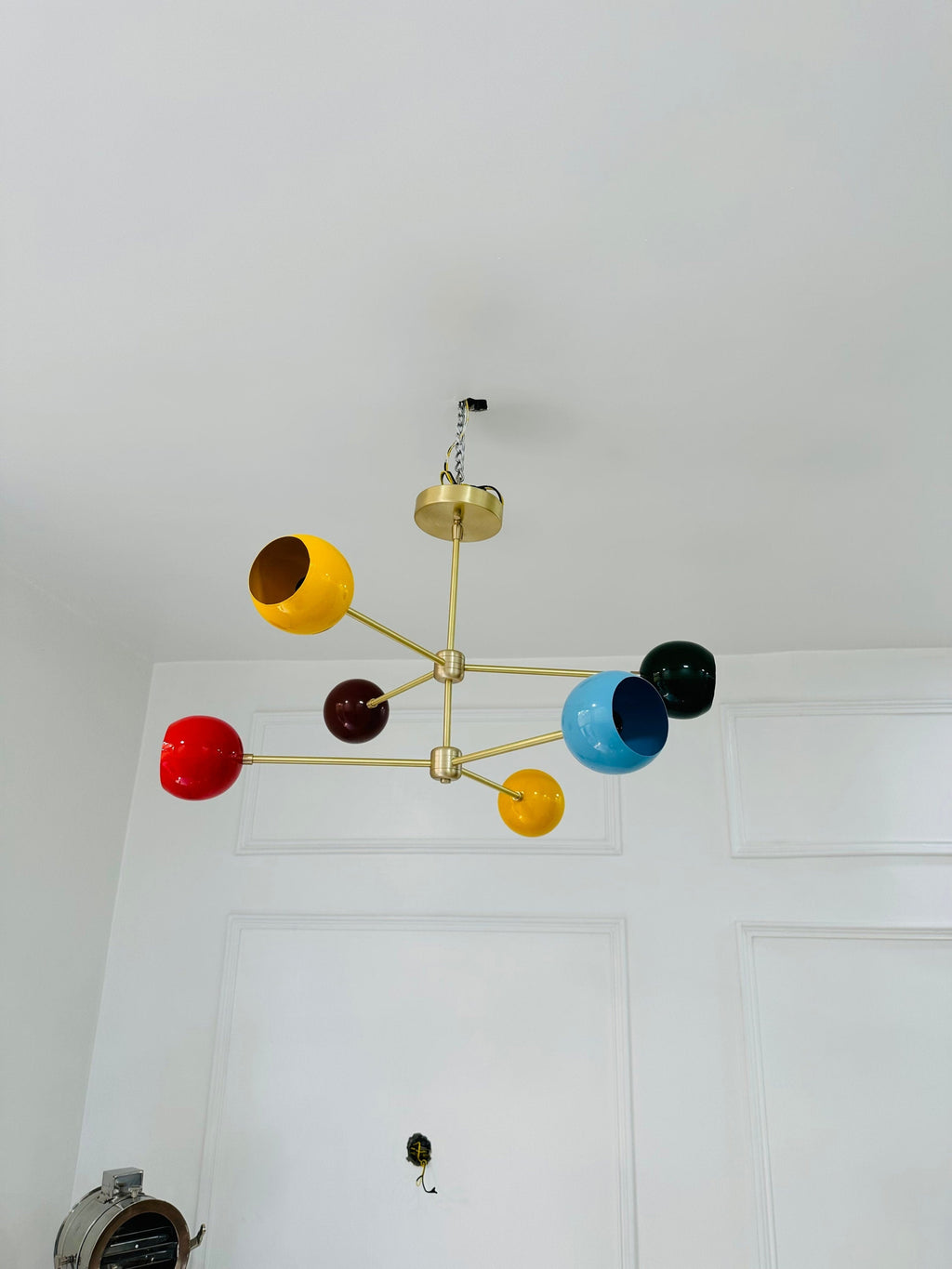 Colorful chandelier with multicolored lampshades on a white ceiling.