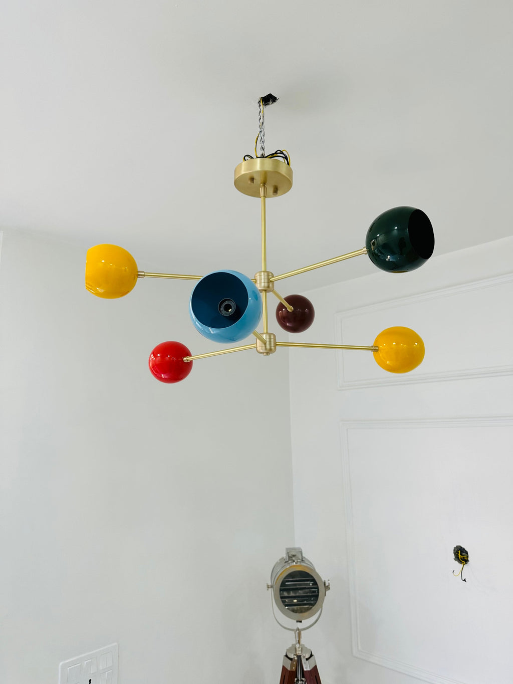 Colorful chandelier with multicolored spherical lights on a white wall.