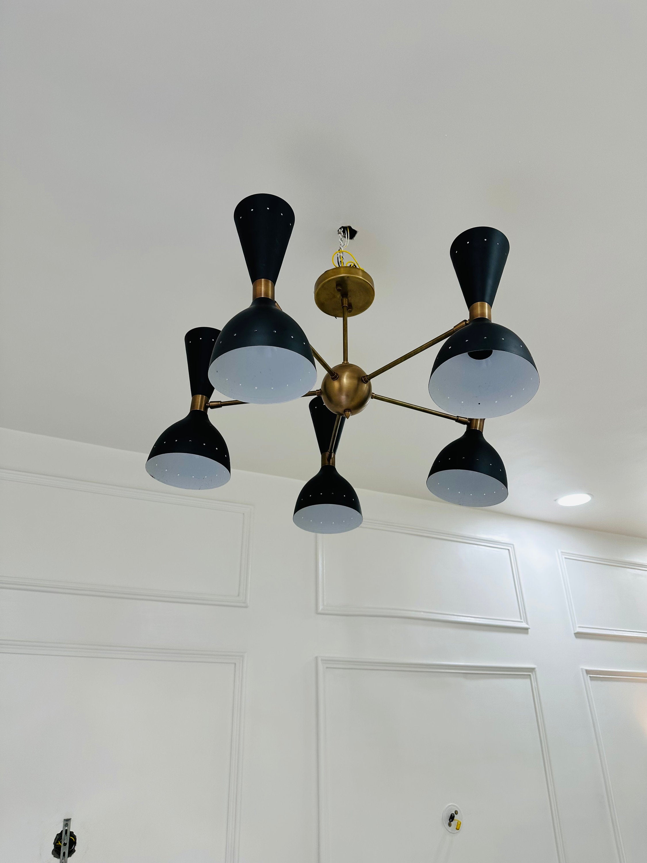 Modern chandelier with black and gold design on a white ceiling