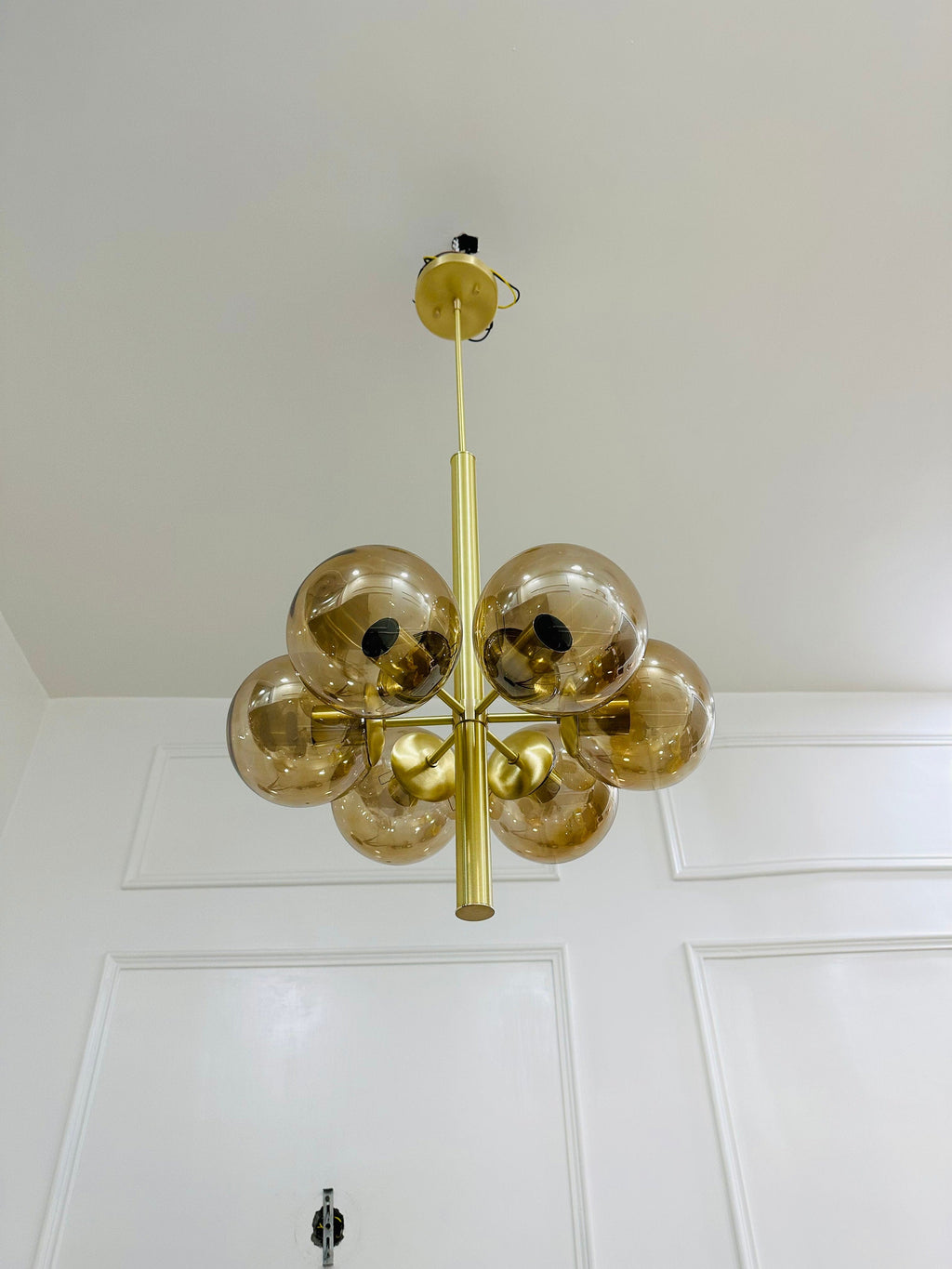 Gold chandelier with glass spheres hanging from a white ceiling.