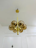 Gold chandelier with glass spheres hanging from a white ceiling.
