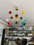Colorful chandelier hanging in a room with shelves displaying various items.