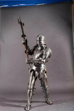 Full-body view of a person in medieval armor holding a spear against a gray background