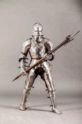 Full-body view of a person in medieval armor holding a spear on a gray background