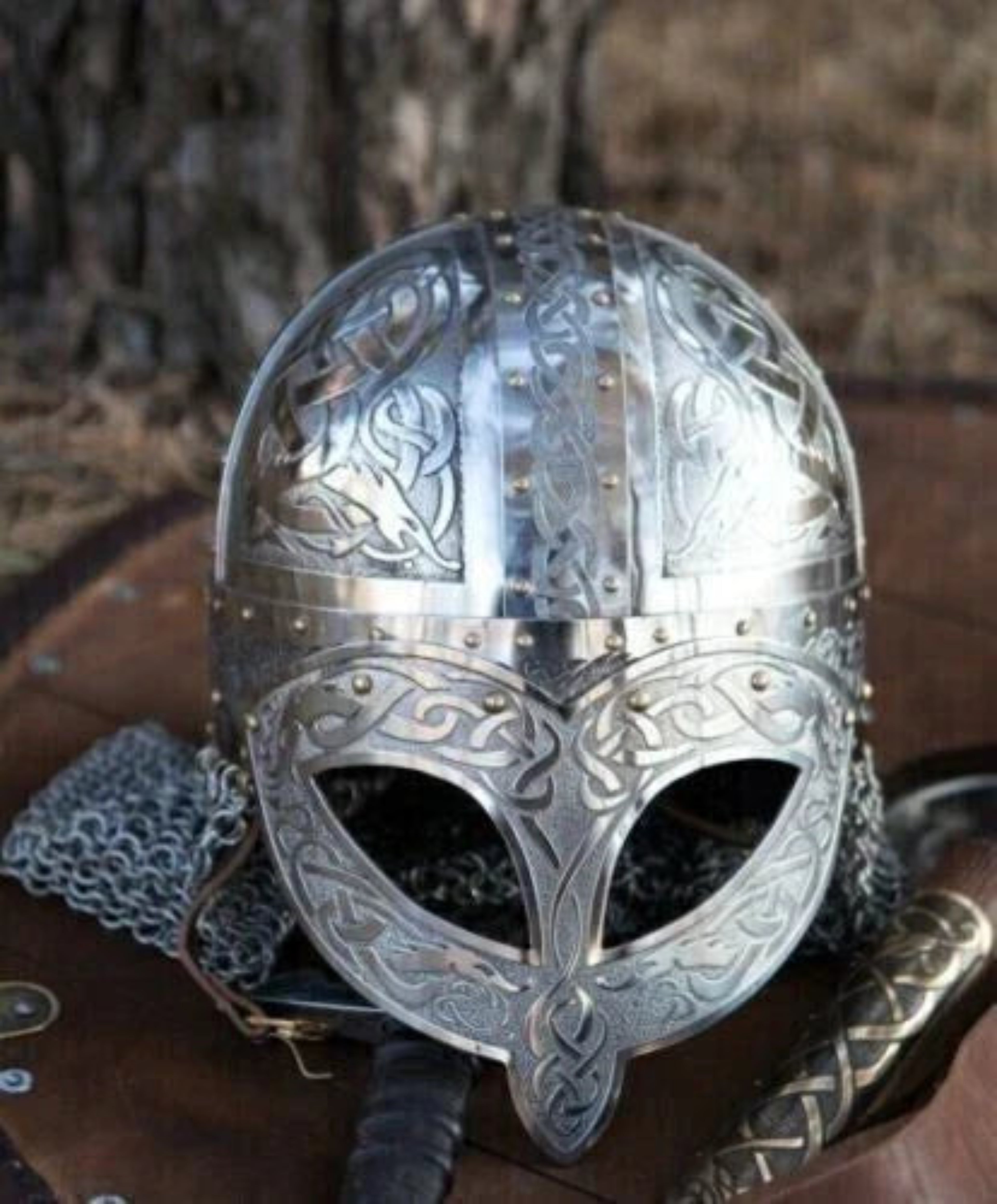 Decorative silver helmet with intricate designs on a wooden surface